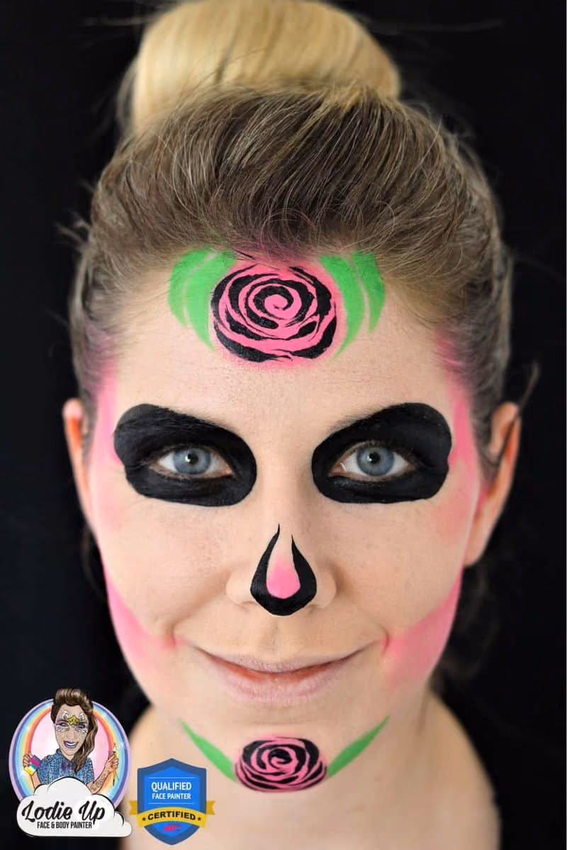 a woman looking at the camera with a sugar skull face paint base and a rose on her forehead and chin