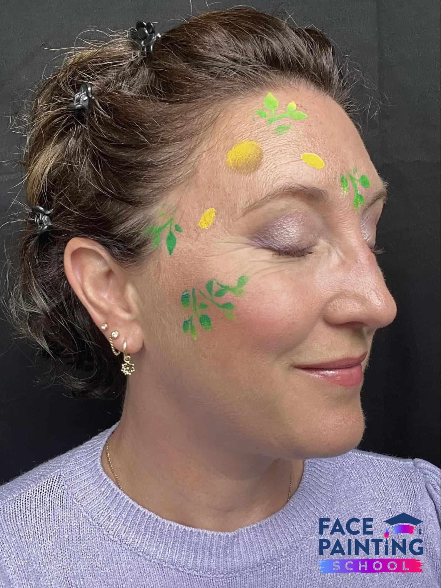 a woman in the beginning stages of creating a flowers face painting on her face