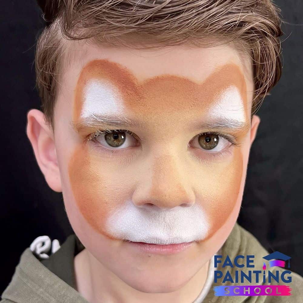 a boy with a base outline of a cheetah face paint design on his face