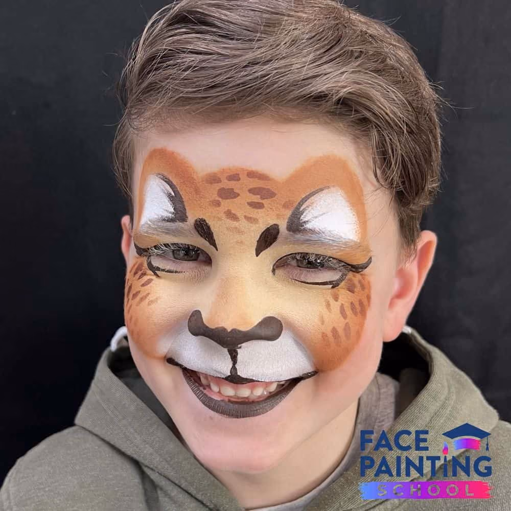a smiling boy wearing a cheetach face paint design