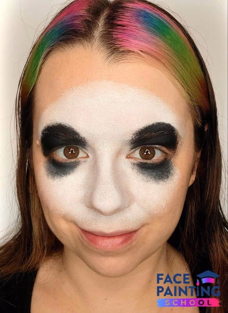 a girl with a white panda face painting base and black paint around her eyes