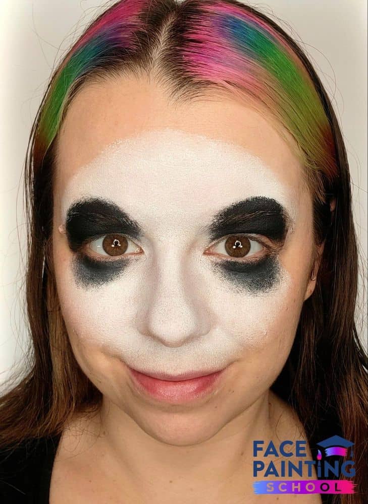 a girl with a white panda face painting base and black paint around her eyes