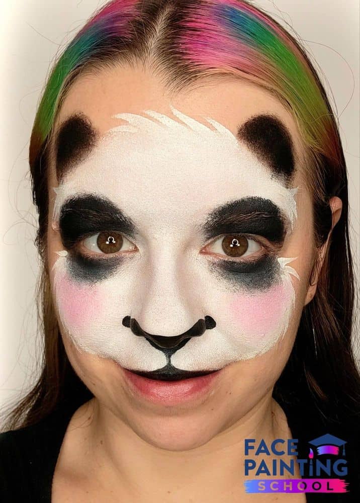 a girl with an unfinished blushing panda face painting