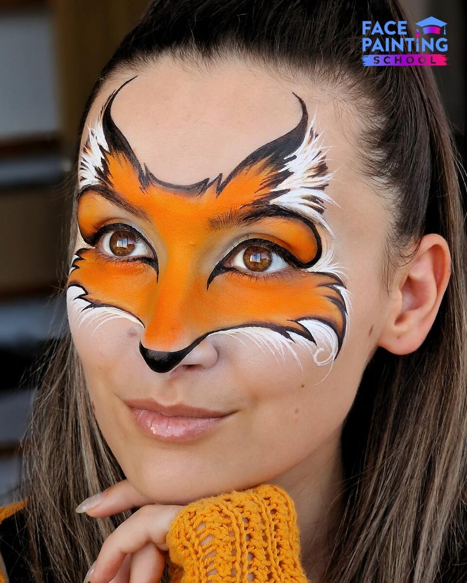 a girl posing for a photo with a fox face paint design