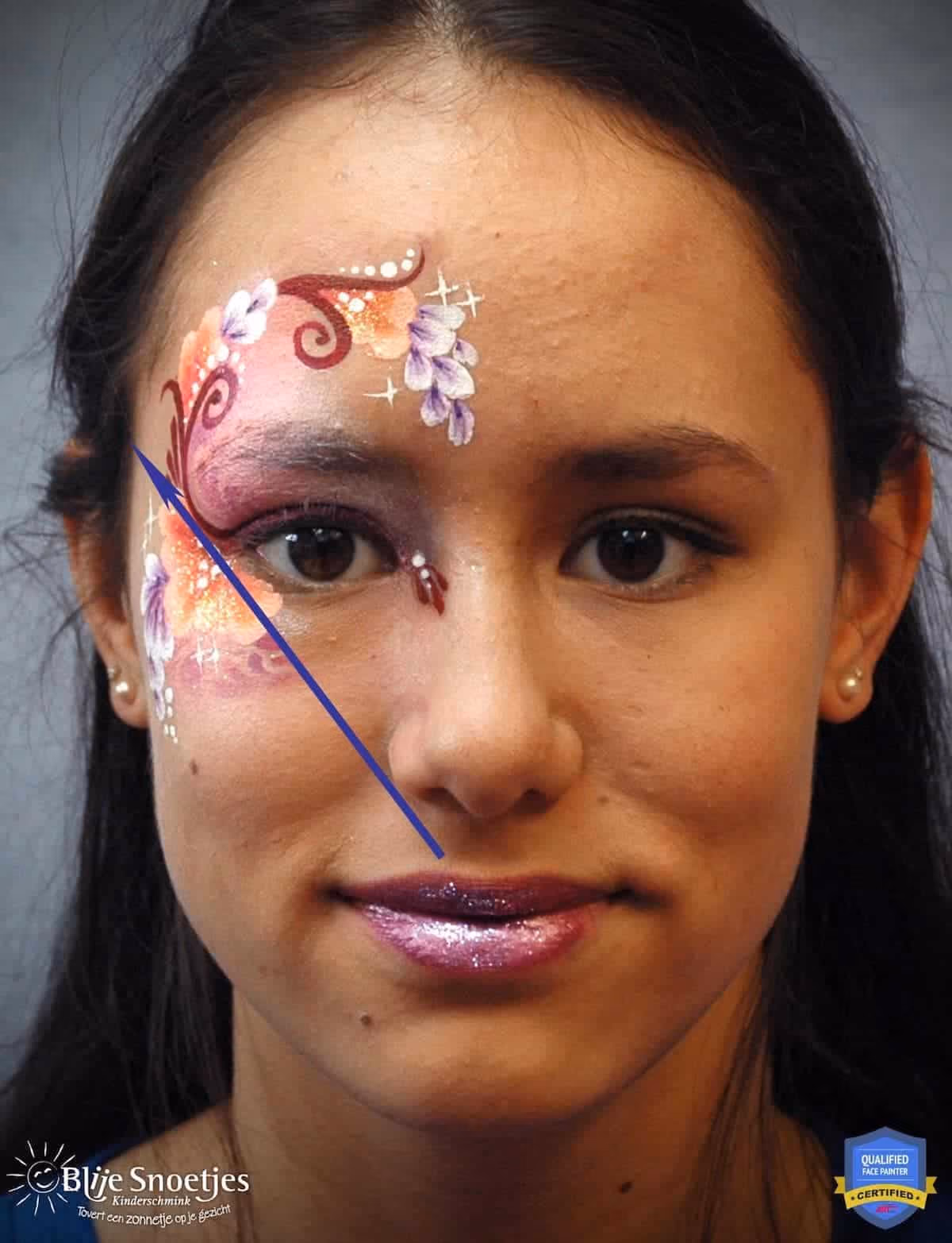 a woman with a compleated fancy eye face paint design with an arrow pointing to the focal point