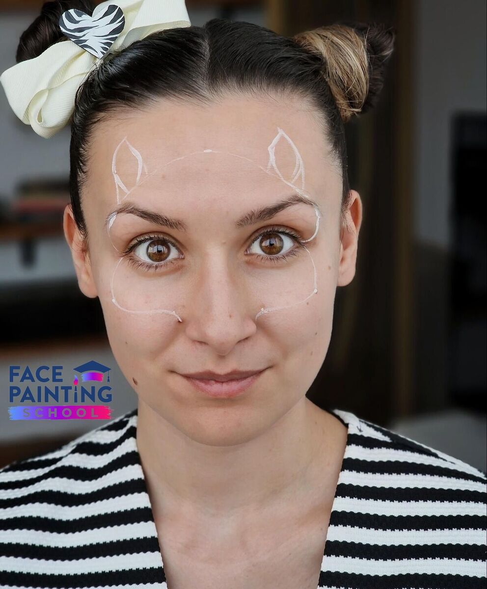 a woman looking at the camera with subtle whitle lines outlining the zebra face paint design