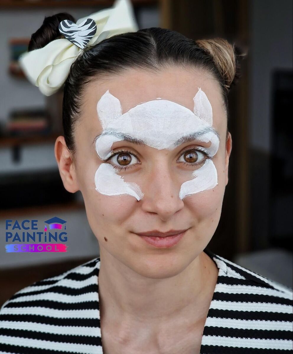 a woman looking at the camera with whitle paint around her nose and eyes