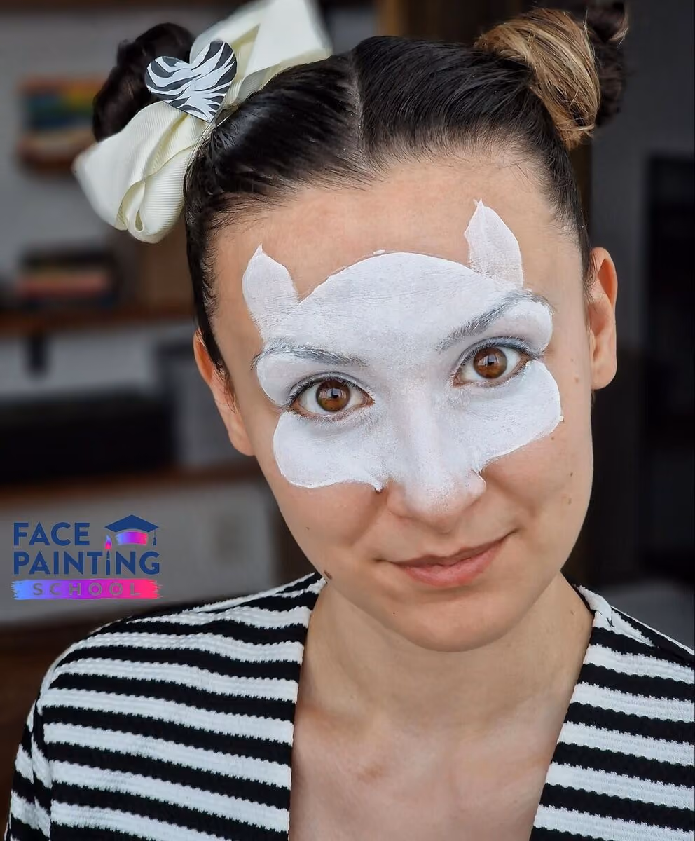 a woman looking at the camera with a compleated base for her zebra face paint desing