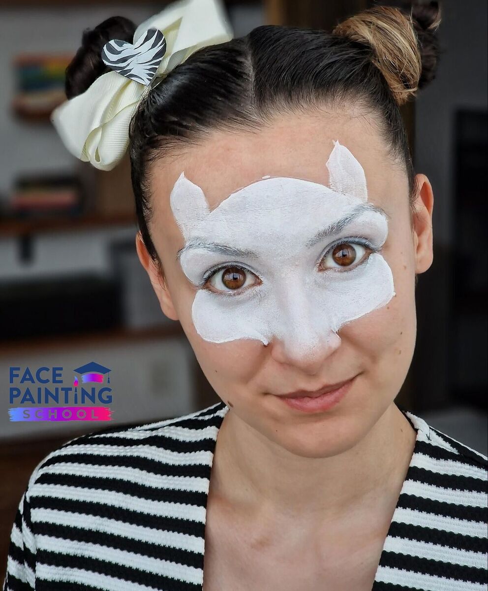 a woman looking at the camera with a compleated base for her zebra face paint desing