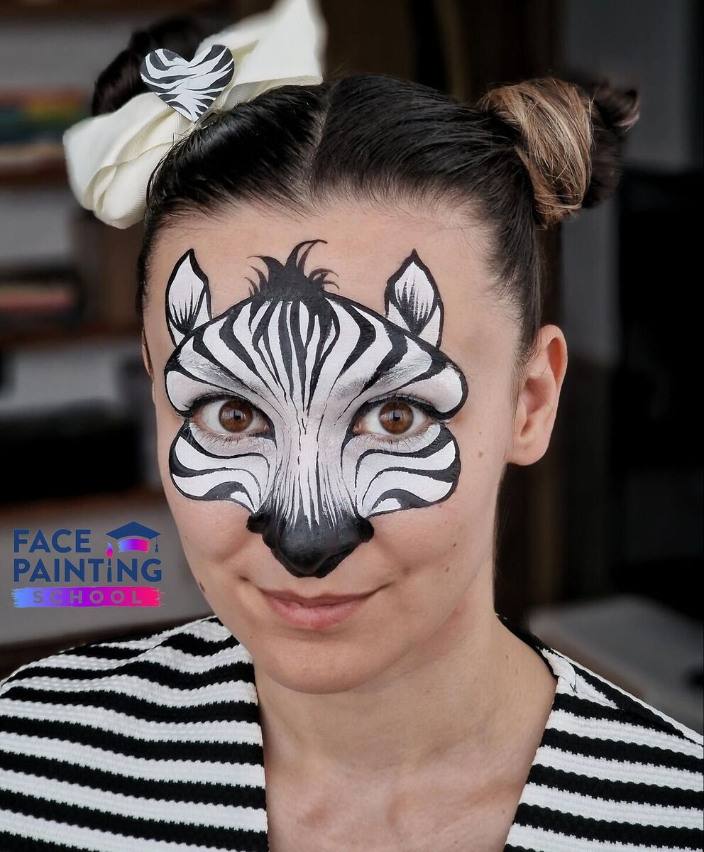 a portrait shot of a woman with a zebra face paint design on her face