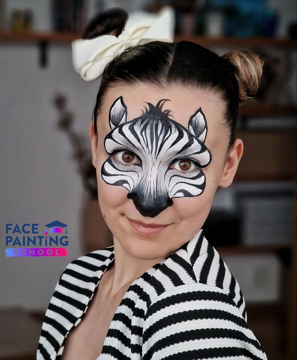 a shot of a woman looking at the camera at an angle with a zebra face paint design on her face
