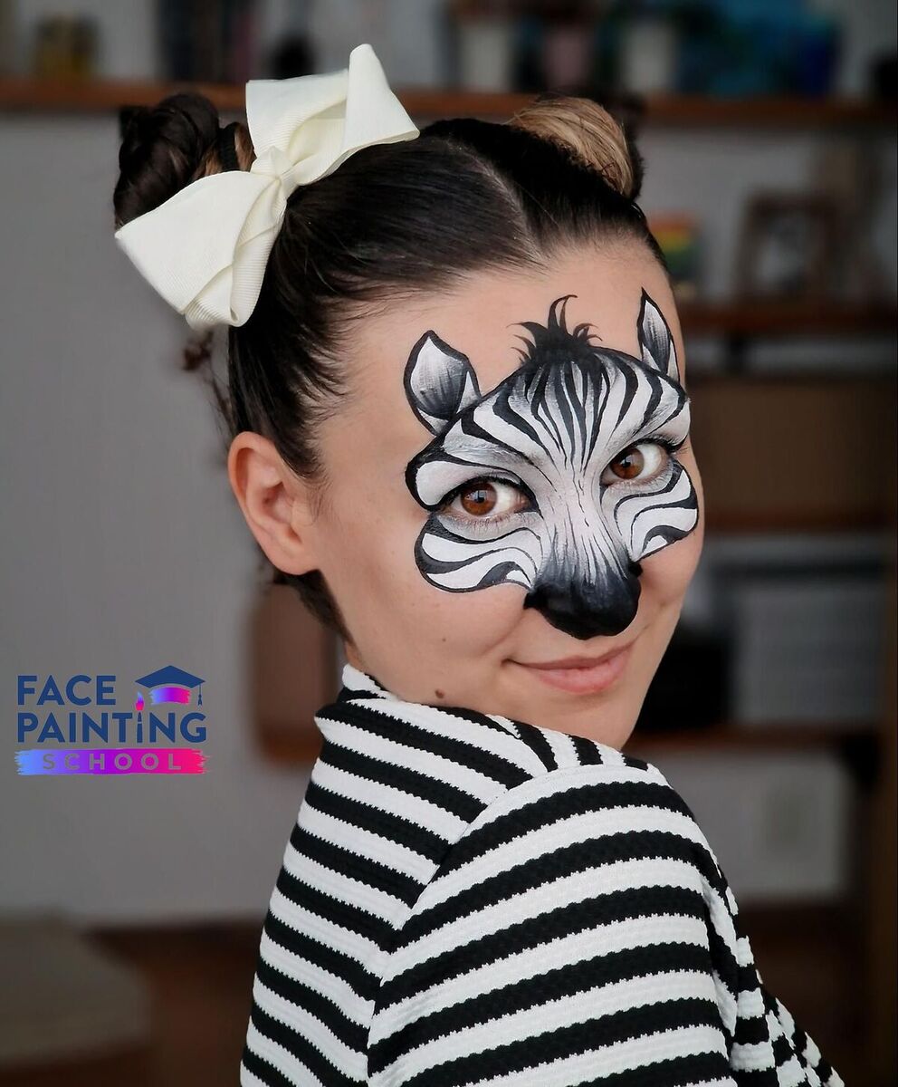 a woman posing with a compleated zebra face paint design on her face