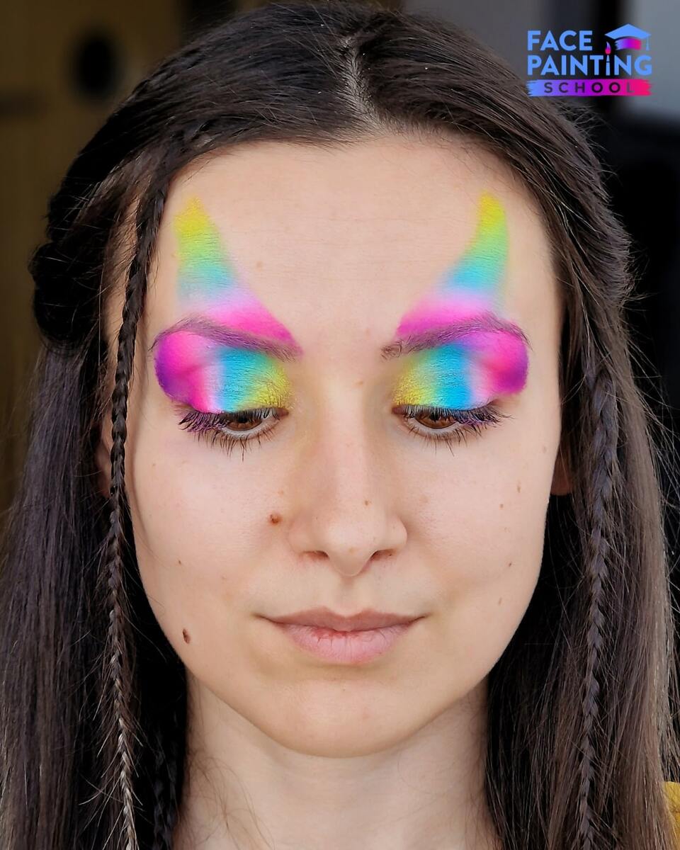 a woman with a shiny rainbow colored paint over her forehead and eyes