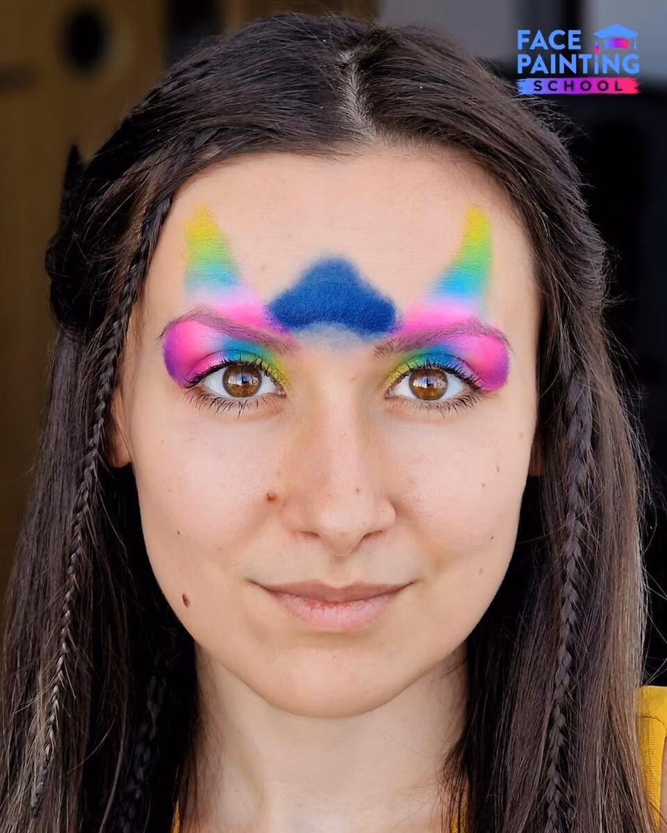 a woman with a shiny rainbow colored paint over her forehead and eyes with blue paint on her forehead