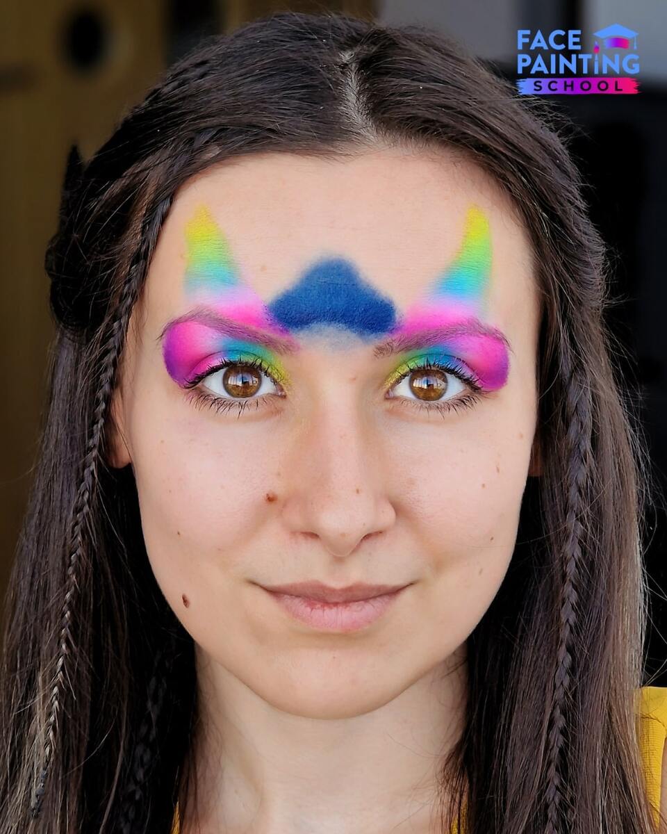 a woman with a shiny rainbow colored paint over her forehead and eyes with blue paint on her forehead