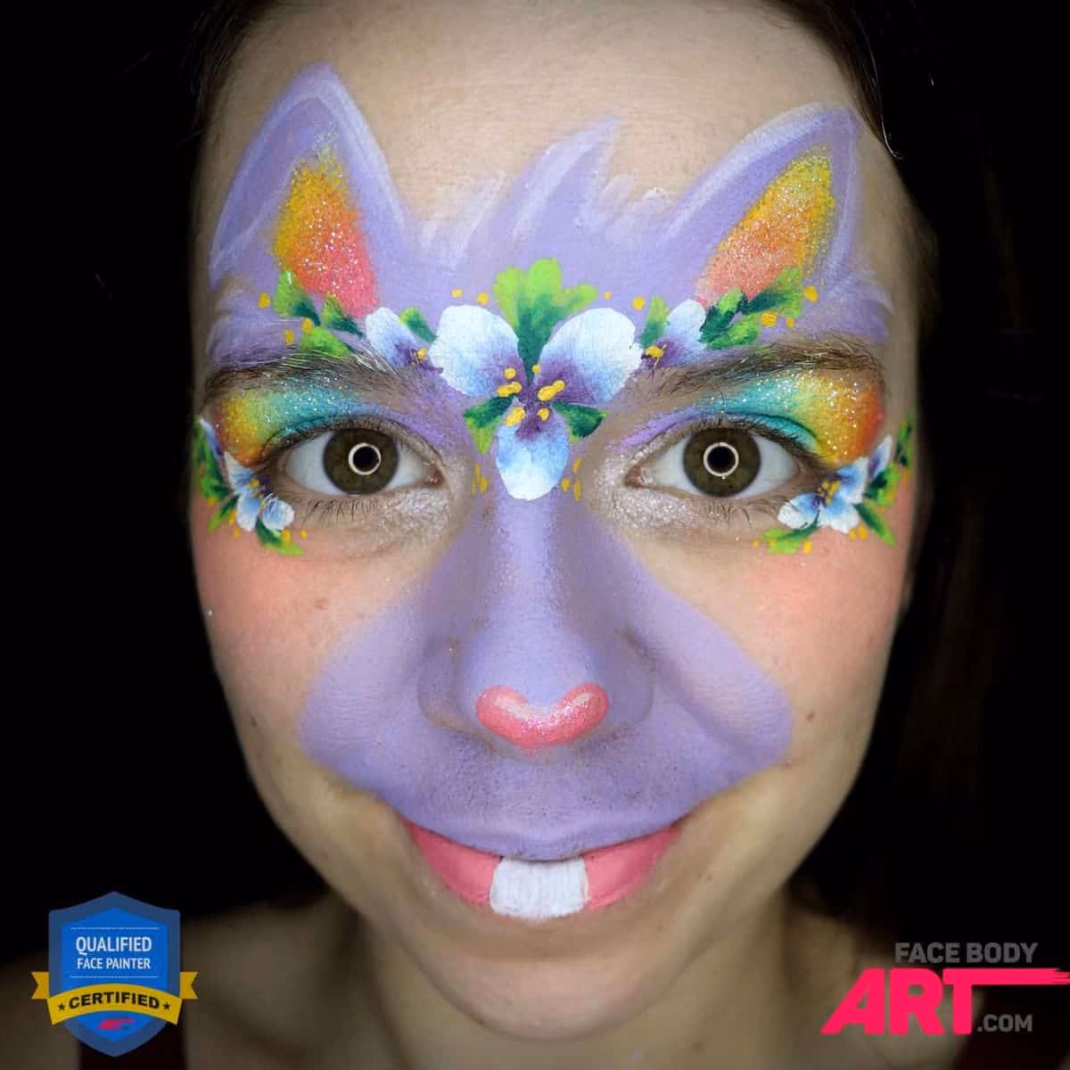 a girl with an almost compleated bunny face painting on her face