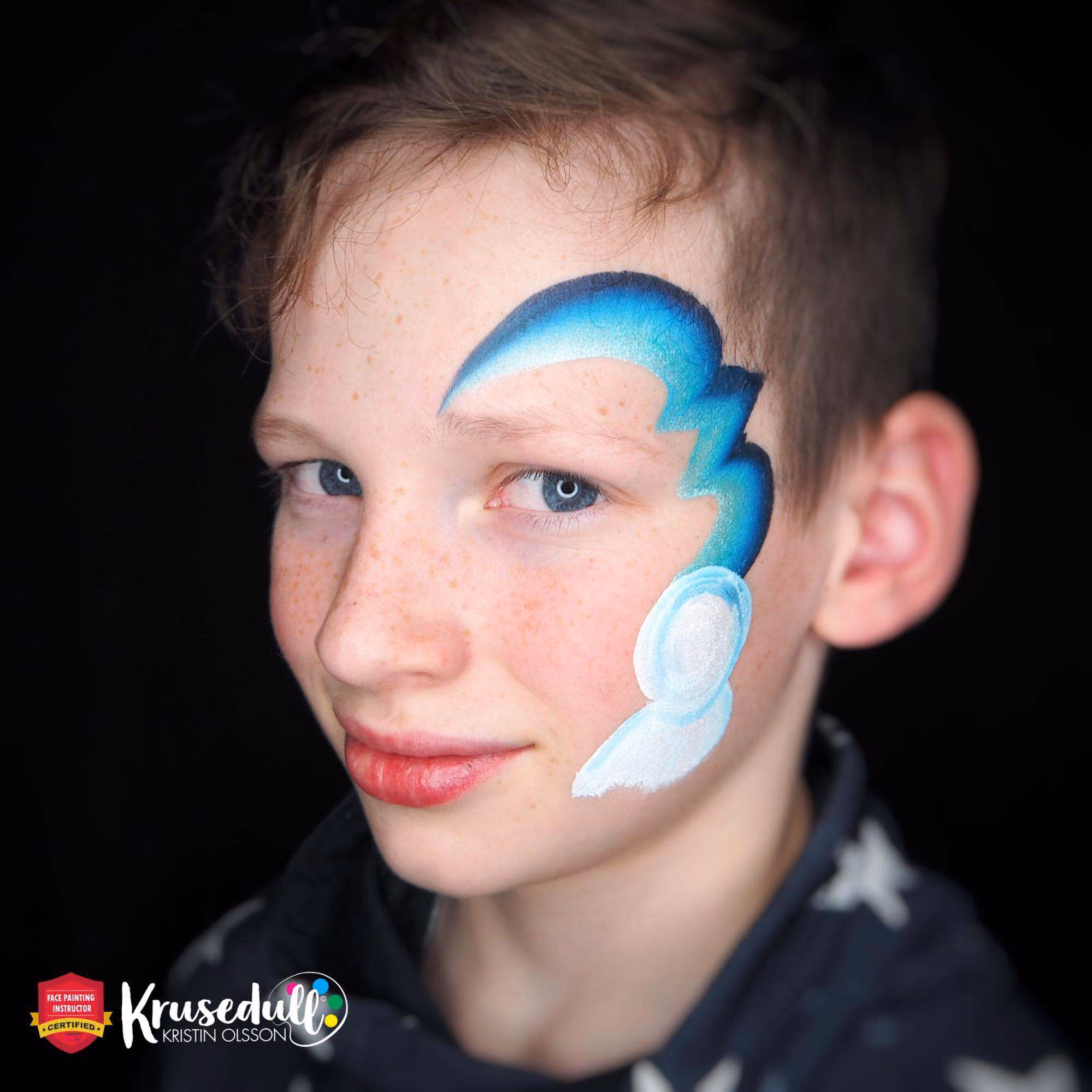 a boy with blue lines painted around his left eye and a base of the snowman