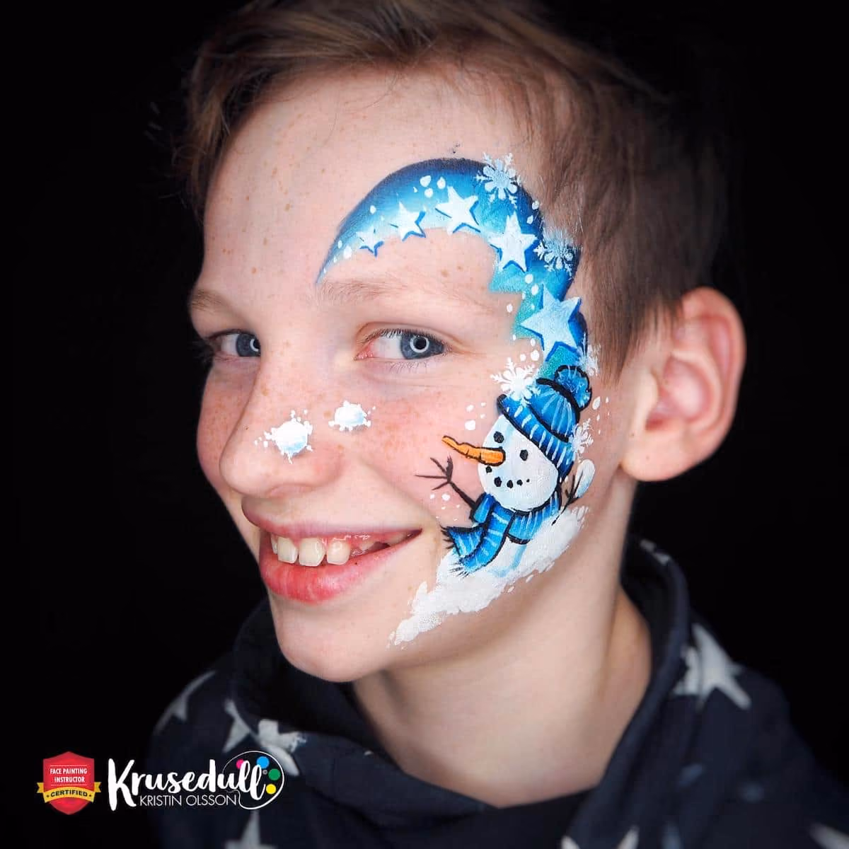 a smiling boy with a completed snowman face paint design