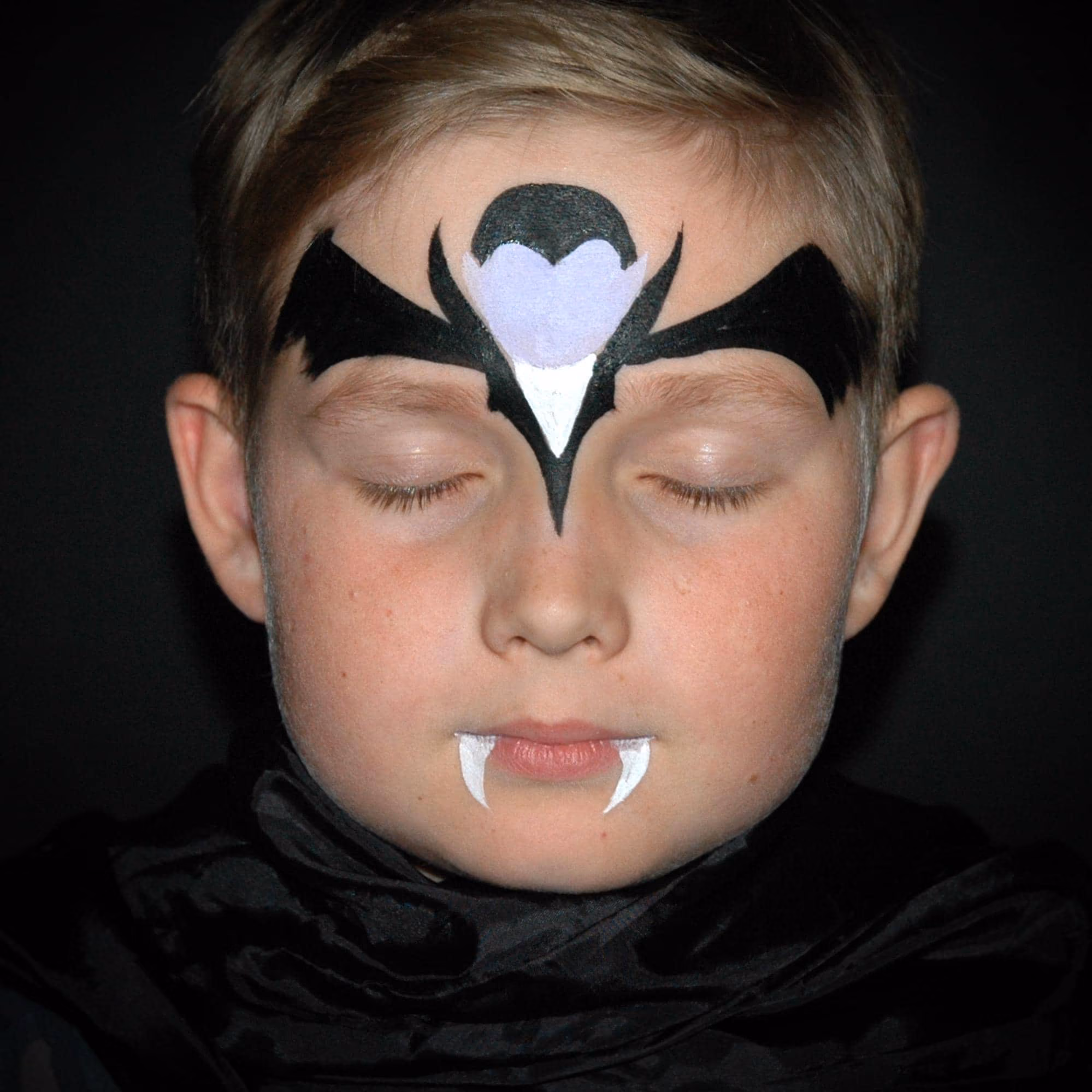 a child with contures of a vampire fape paint on his forehead