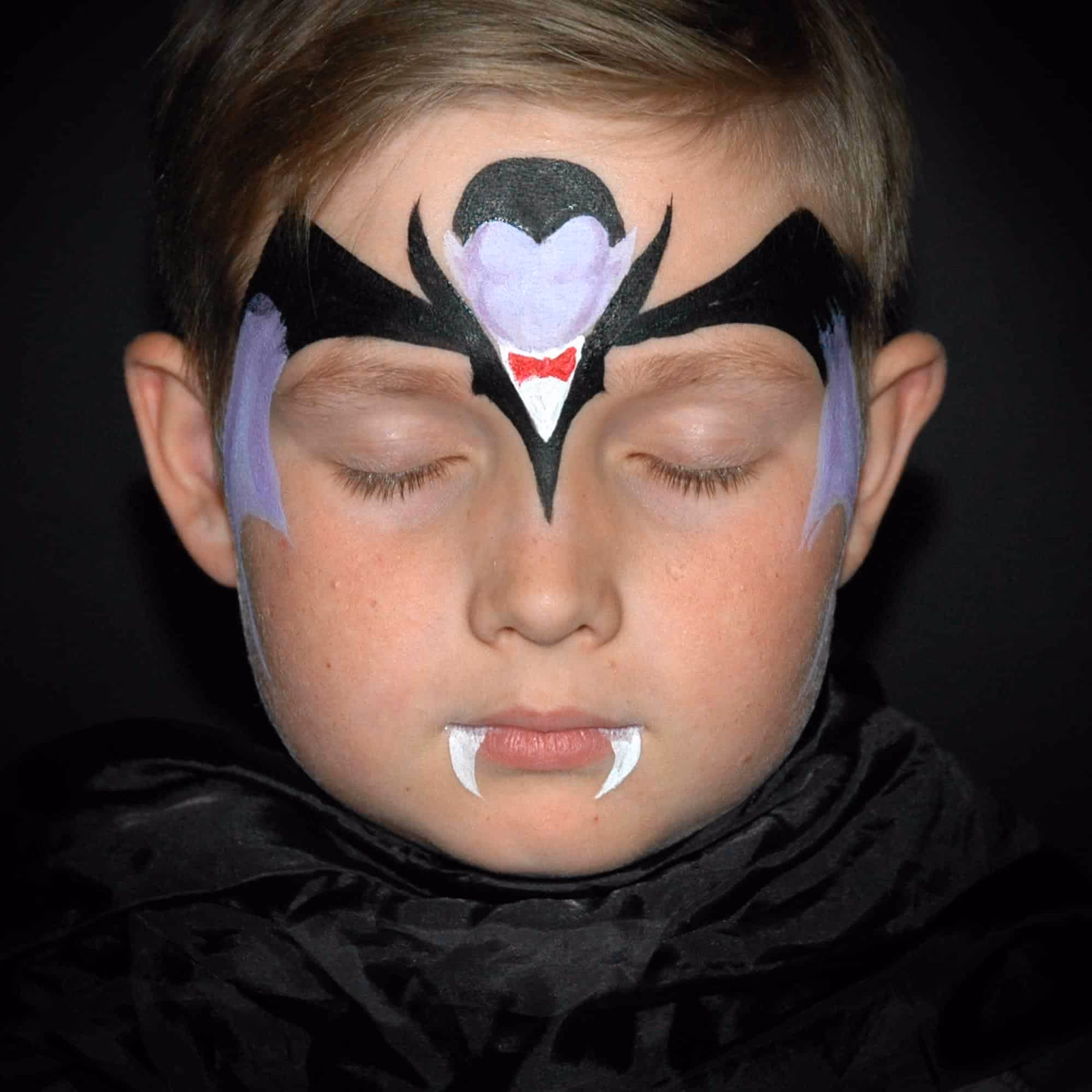 a child with detailed contures of a vampire fape paint on his forehead