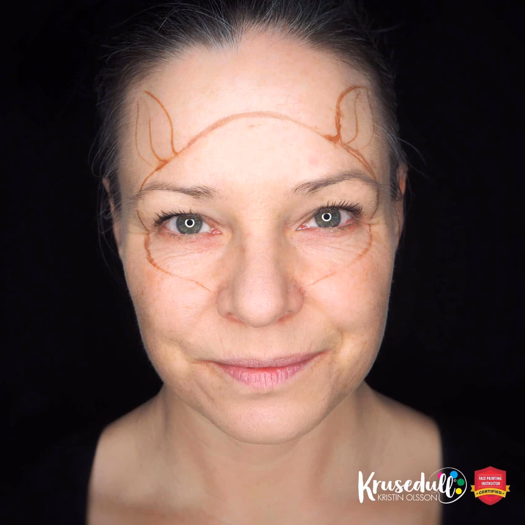 woman looking at the camera with a conture of a reindeer painted on her face