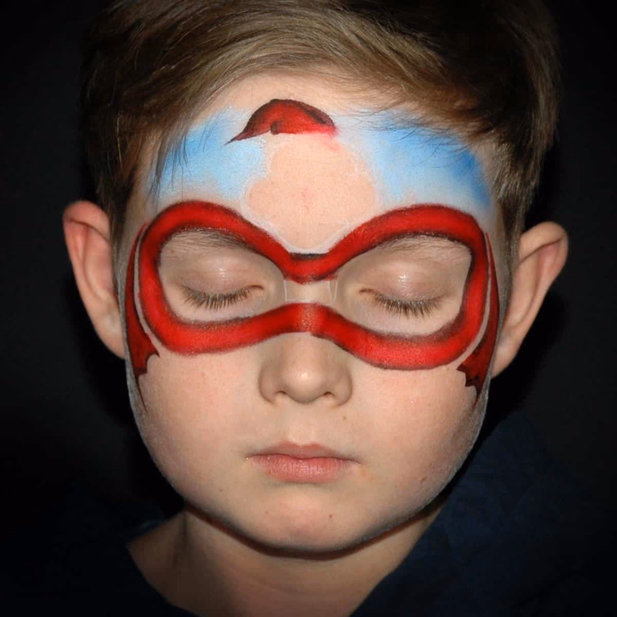 a boy with a santa face paint around his eyes and on his forehead that is in the starting phase