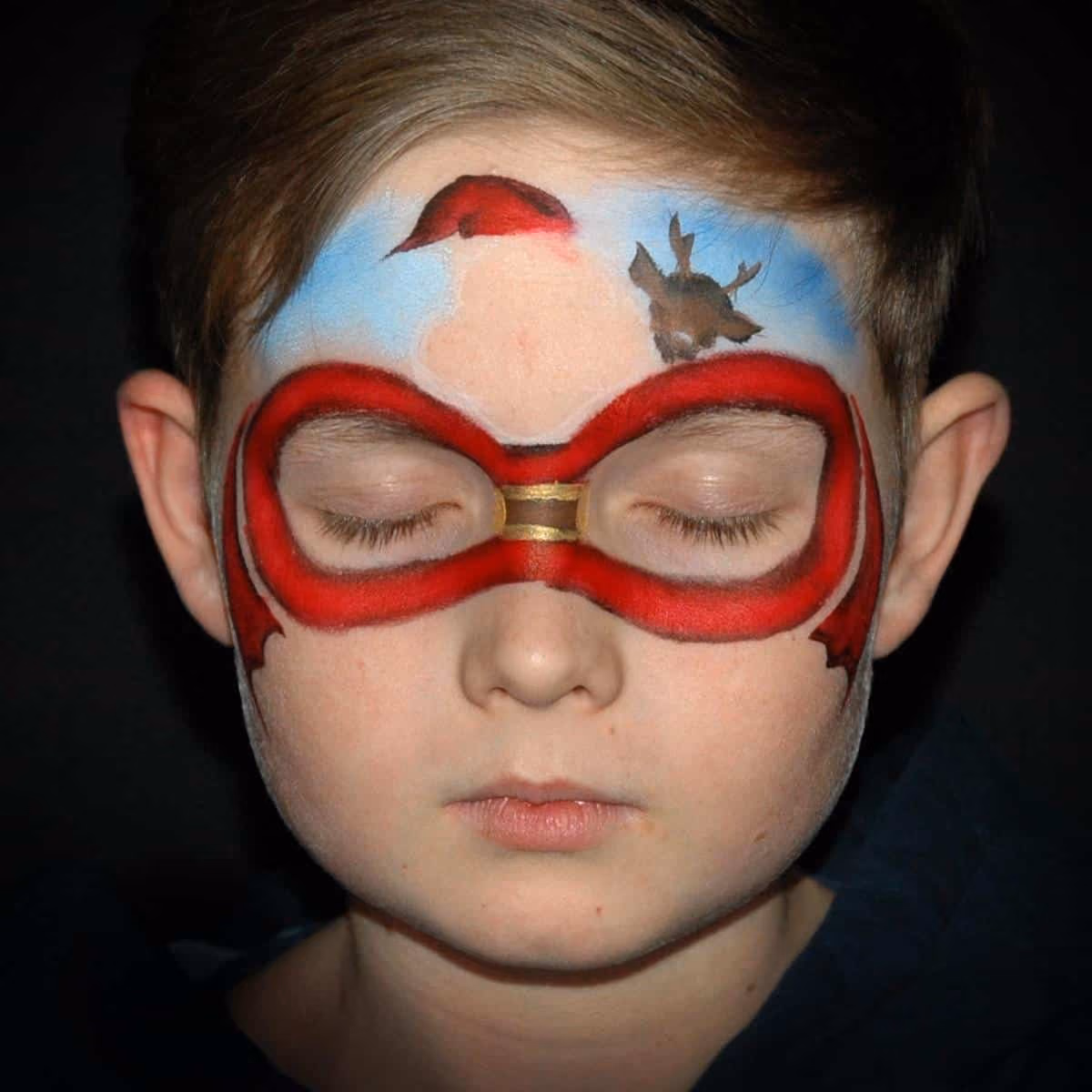 a boy with a santa face paint around his eyes and on his forehead with an added reindeer