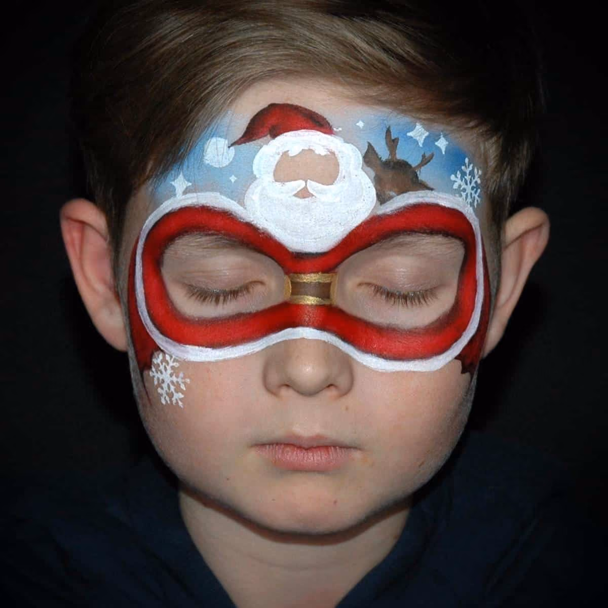 a boy with a santa face paint around his eyes and on his forehead with an added santa clause