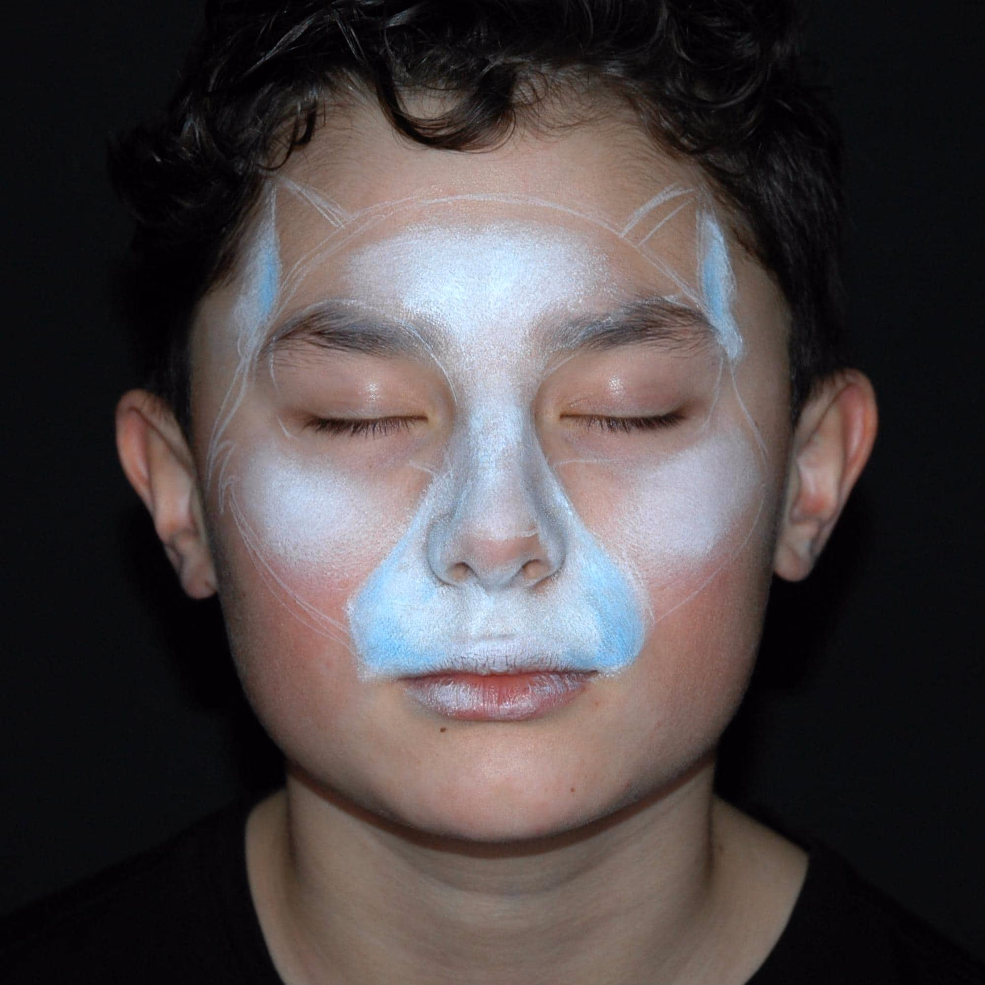 a boy with his eyes closed with a semi-filled outline of the halloween cat face painting