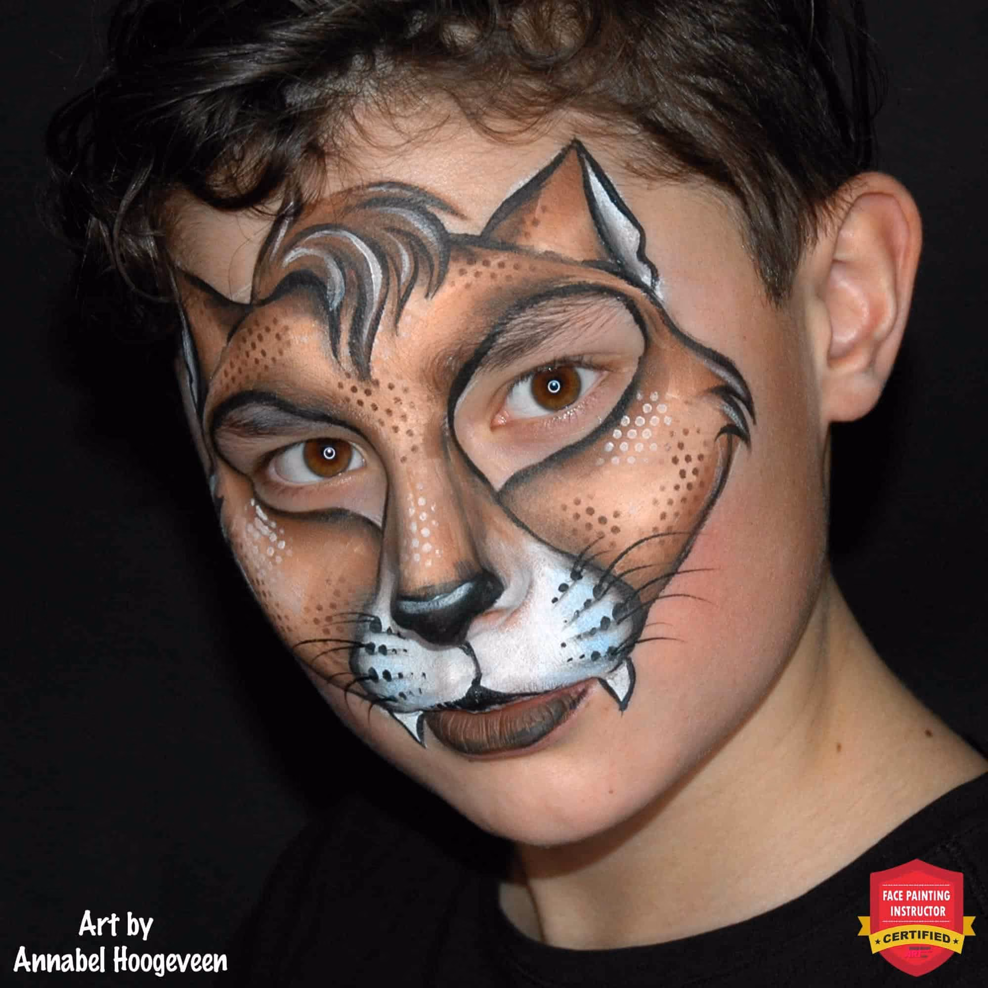 a boy looking at an angle with an compleated halloween cat face painting