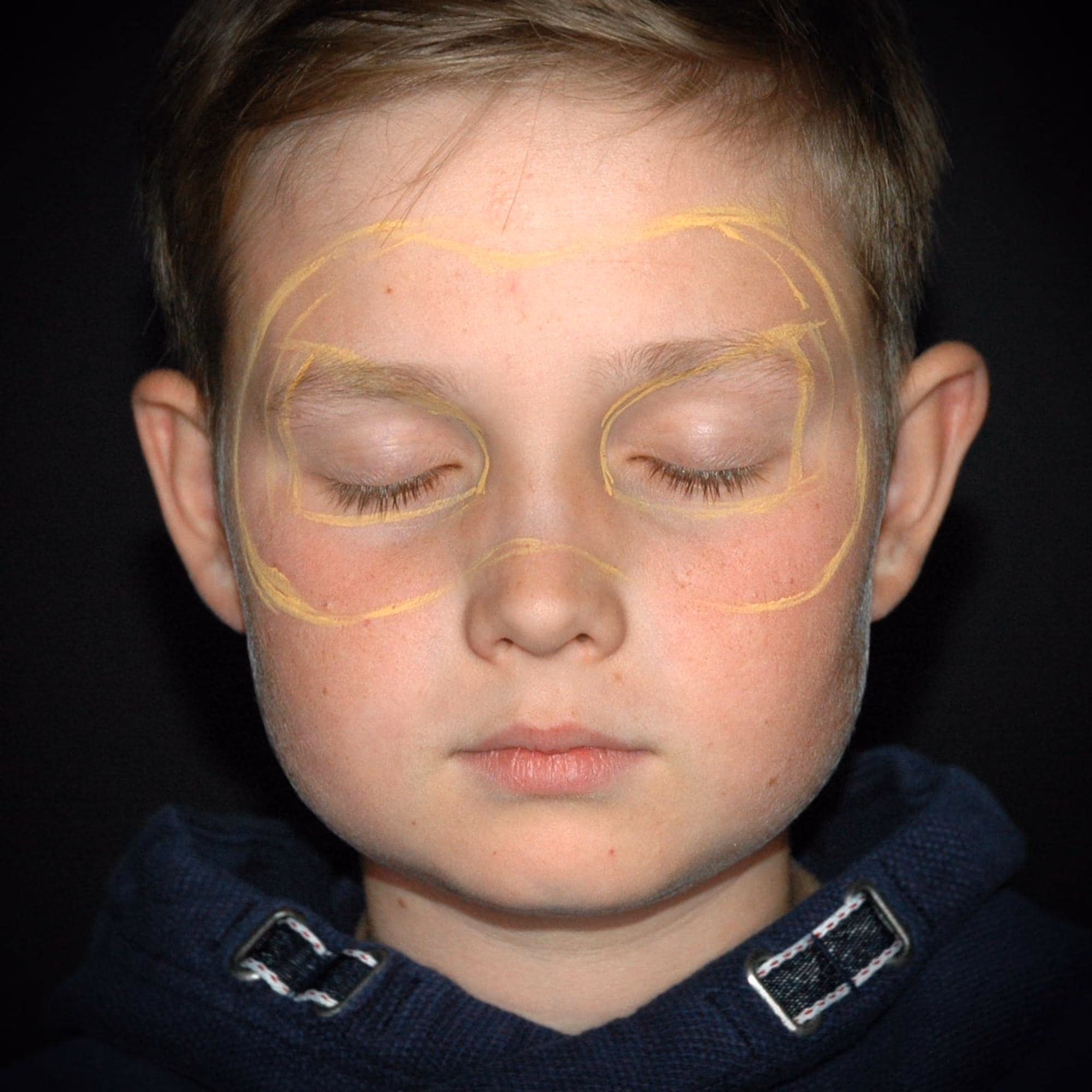 a boy with an outline of a pumpkin face paint design