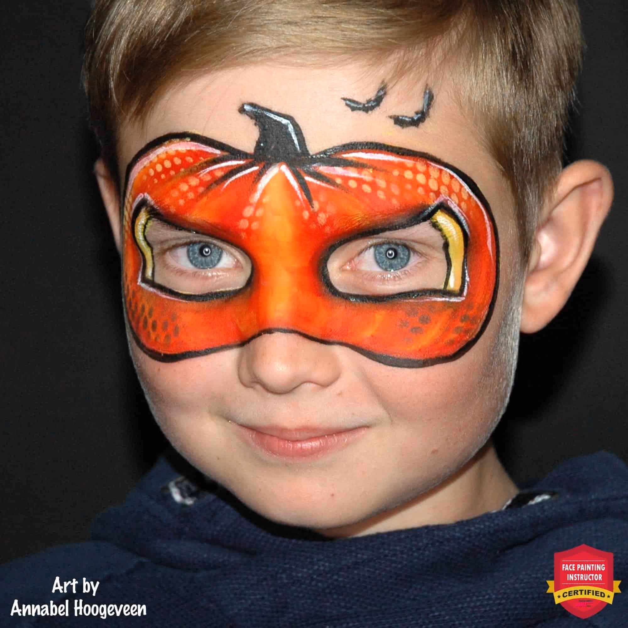 a boy looking at the camera at an angle with a pumpkin face paint