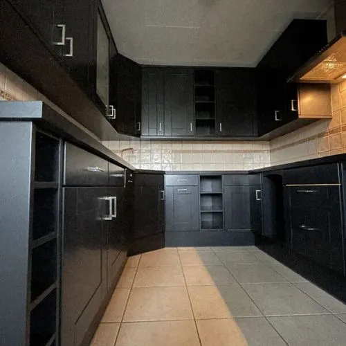 A kitchen with black cabinets and tile flooring.