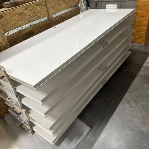 A stack of white plywood boards in a warehouse.