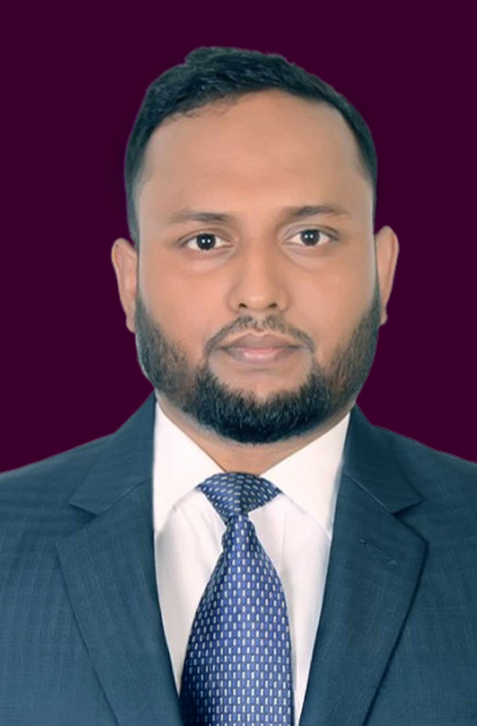 Man with a beard wearing a blue suit, white shirt, and patterned blue tie against a dark purple background.
