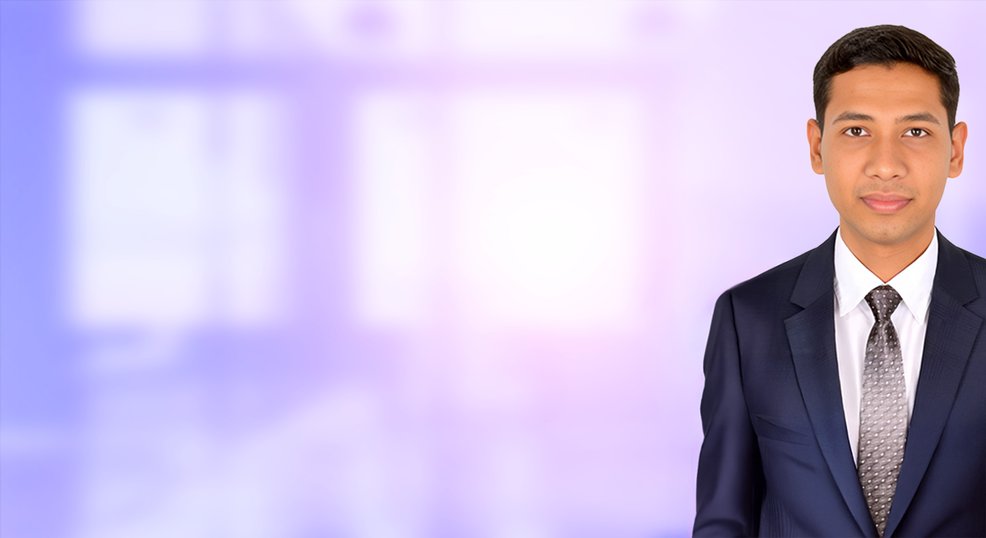 Portrait of a young man wearing a dark suit, white shirt, and patterned tie against a blurred purple and white background.