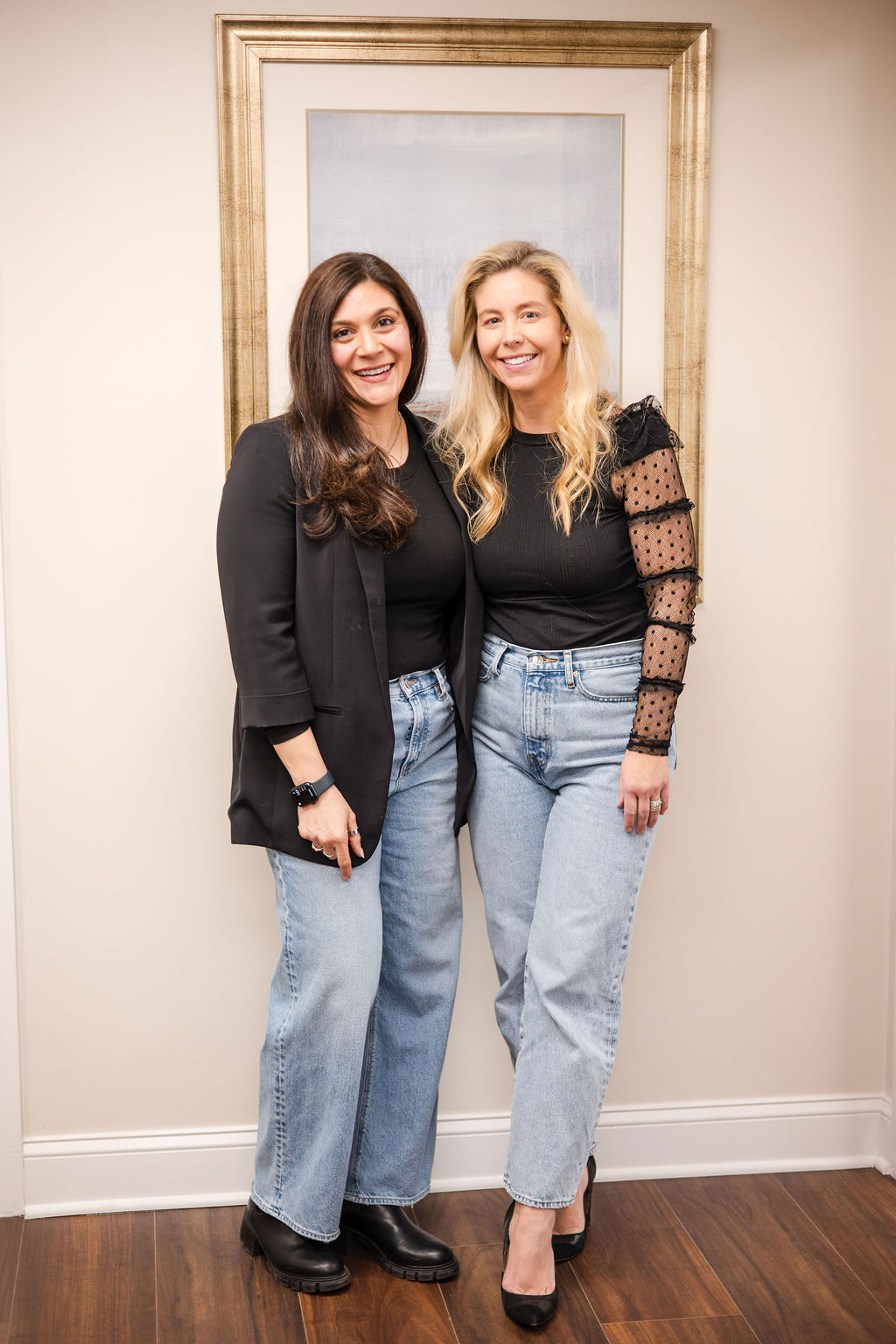 All of Living Well Counseling Center's therapy providers standing in a doorway, all wearing black tops and blue jeans, smiling in an office with wood flooring.
