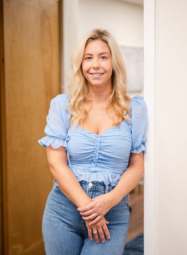 All of Living Well Counseling Center's therapy providers standing in a doorway, all wearing black tops and blue jeans, smiling in an office with wood flooring.