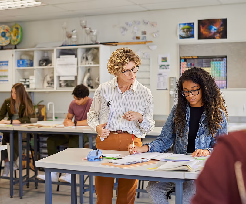 Collaborative classroom setting - A group of students sitting and working together around a table, with two women engaging in discussion or study, suggesting a collaborative educational environment.