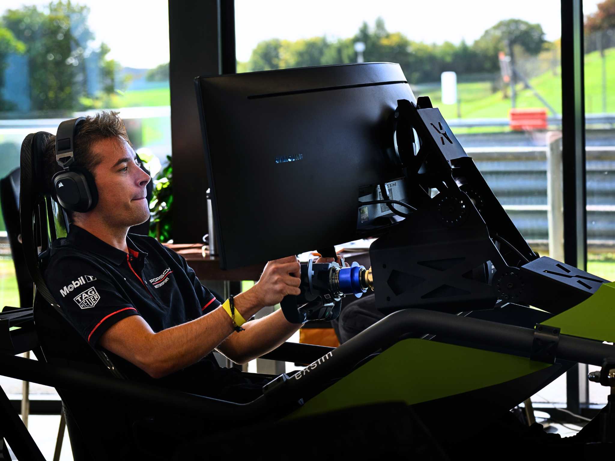 Man wearing headphones focused on a racing simulator with steering wheel and large screen.