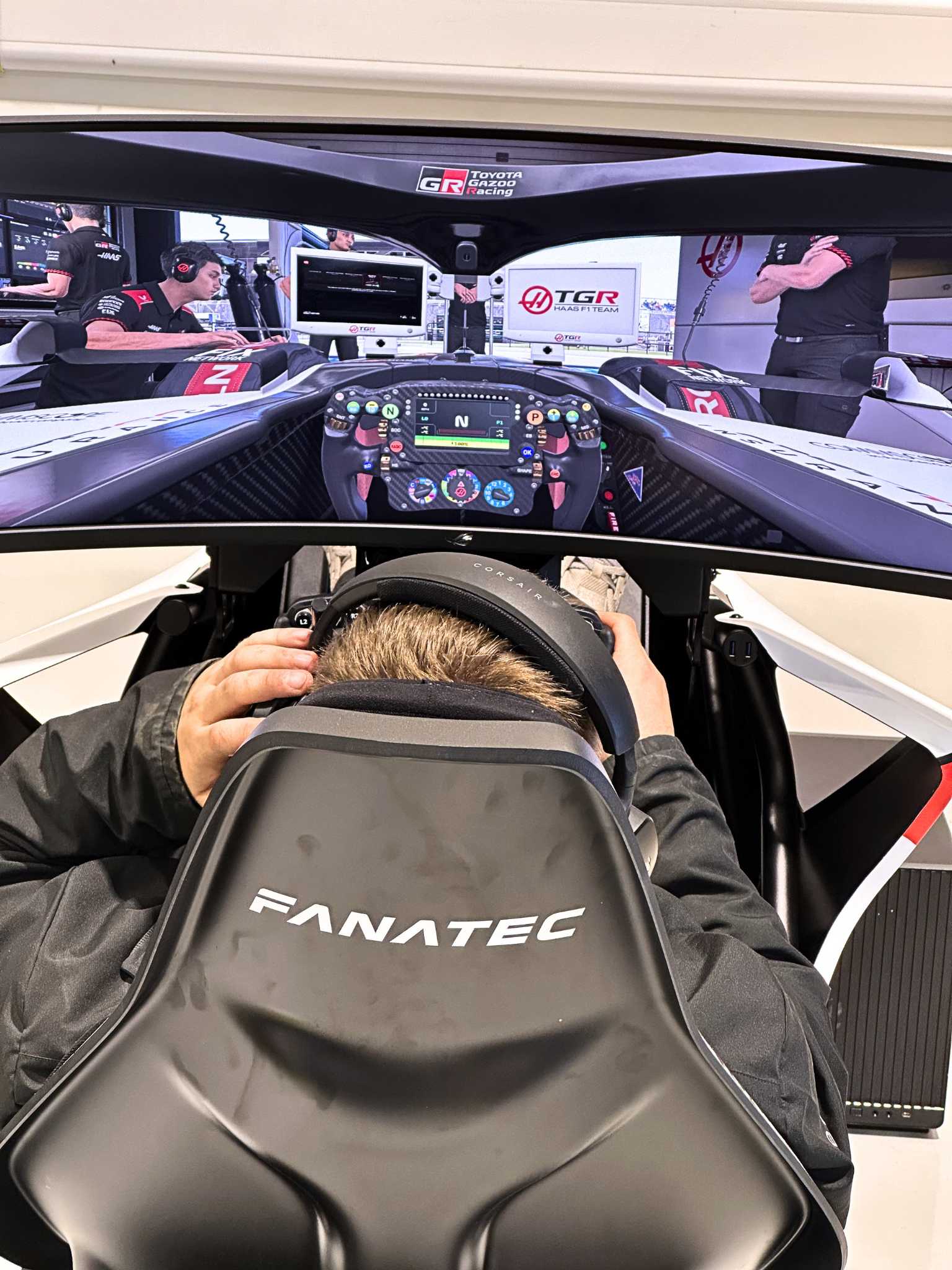 Person using a Fanatec racing simulator setup with a curved screen showing a Toyota Gazoo Racing cockpit view.
