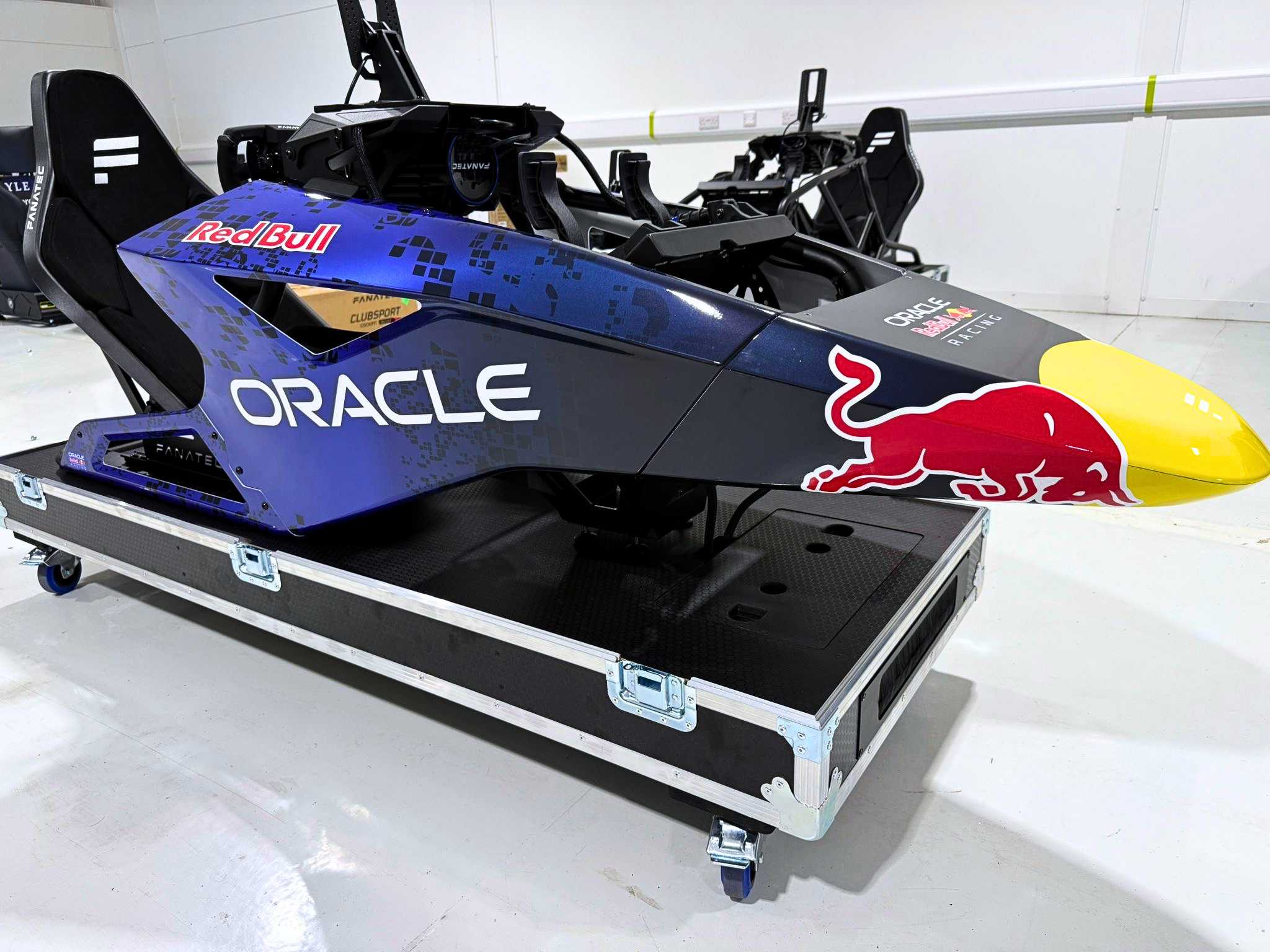 Blue Oracle Red Bull Racing simulator cockpit on a wheeled black platform case.