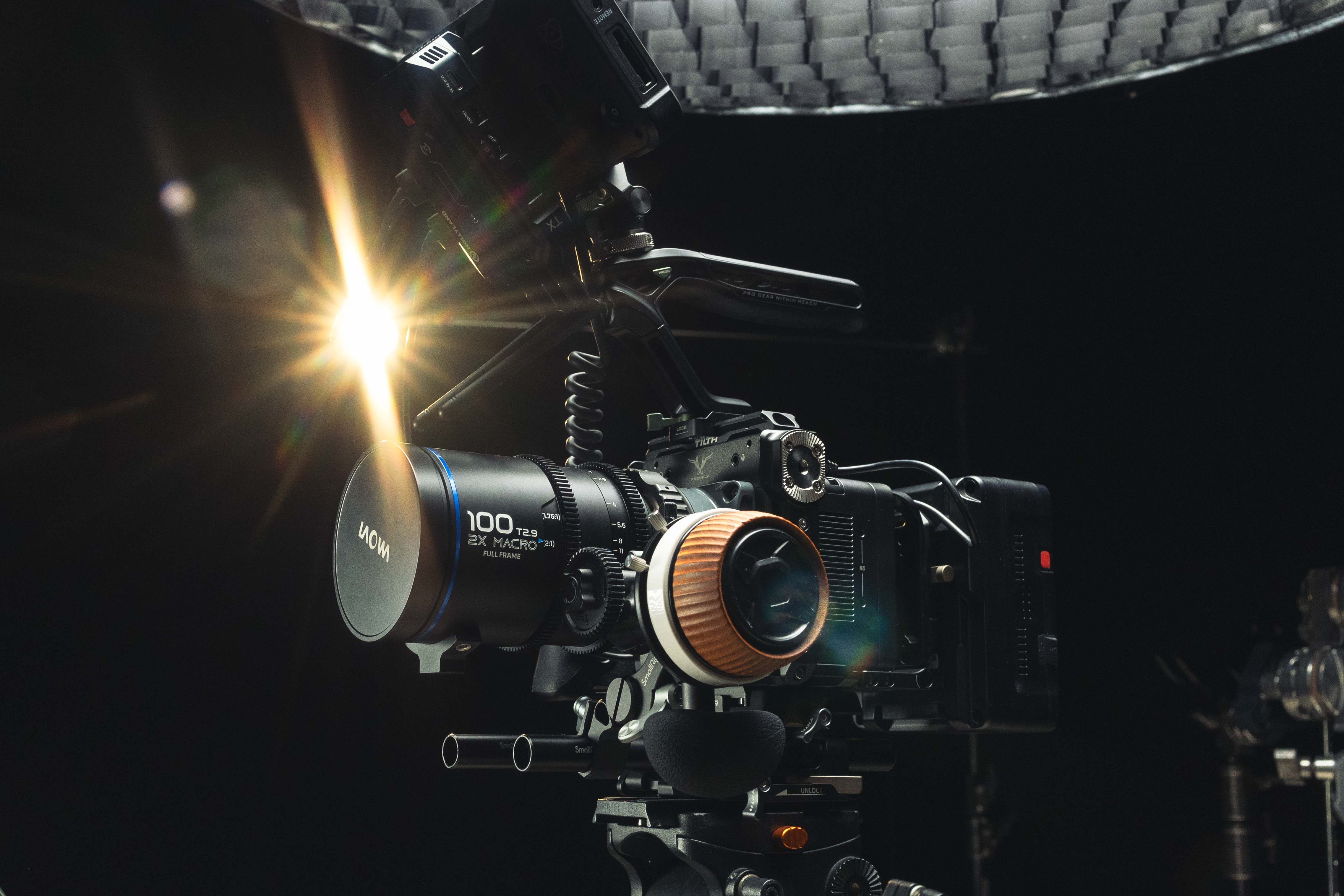 Freefly ember s5k with a 100mm T2.9 macro lens set against a dark background with bright studio light flare.| MMNT PRODUCTIONS