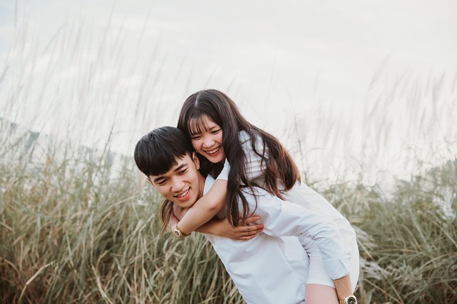 Jeune couple riant dans la nature pendant un moment complice lors d’un voyage en amoureux.