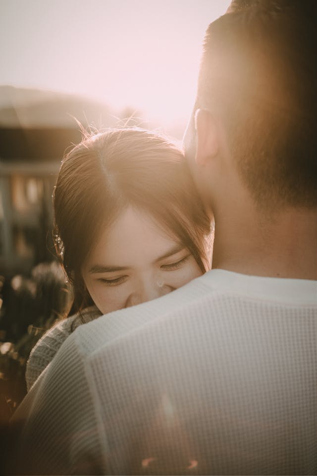 Gros plan d'une femme blottie contre l'épaule d'un homme, les yeux fermés, dans un moment de tendresse et de proximité.