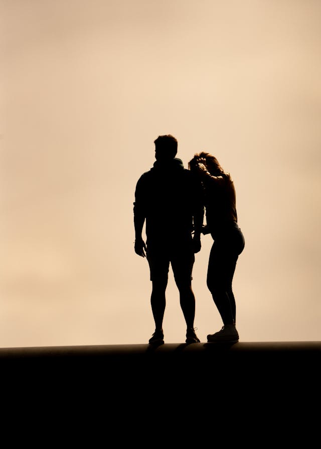 Silhouette d'un couple enlacé sur un fond clair et uniforme, l'un blotti contre l'autre.