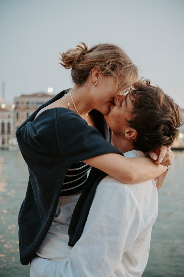 Couple s'embrassant avec tendresse au bord de l'eau, ambiance douce.