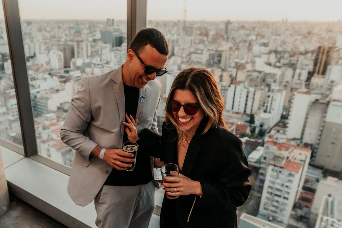 Un couple rigolant avec un verre à la main, en date