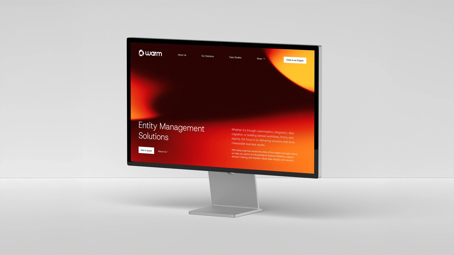 Computer monitor displaying a website homepage with orange and red gradient background titled 'Entity Management Solutions' and options like About Us, Our Solutions, Case Studies, and a Chat to an Expert button.