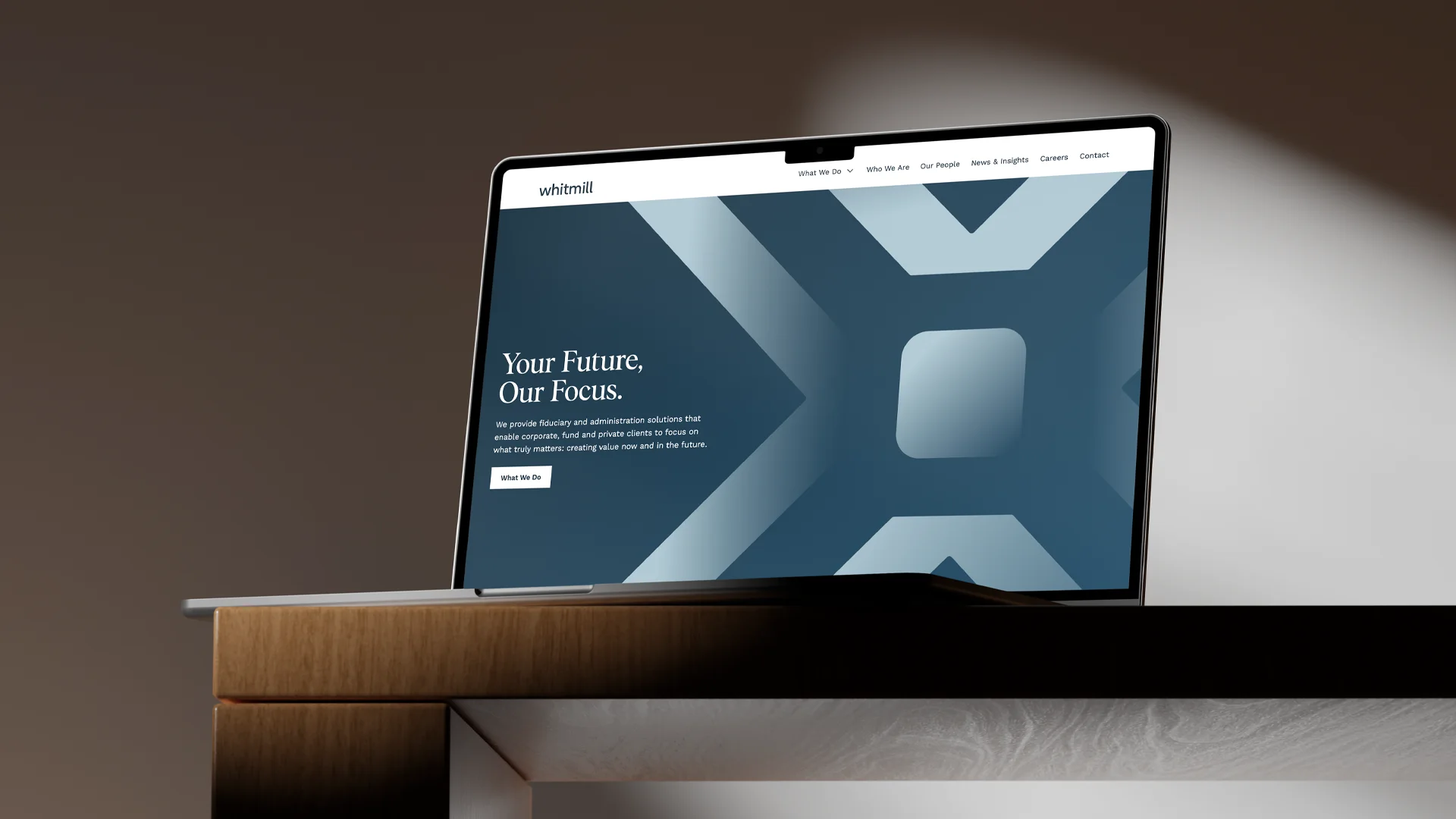 Open laptop on a wooden desk displaying a website homepage with the title 'Your Future, Our Focus.' and a blue geometric background pattern.